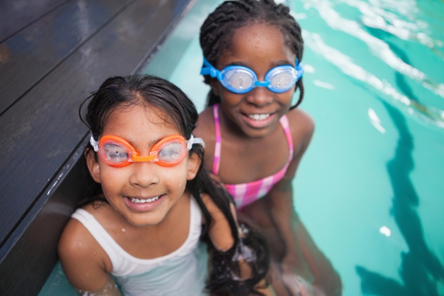two young girls sitting in pool with goggles img